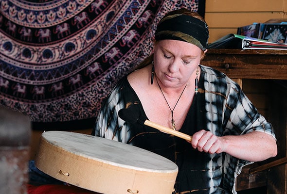 A handheld drum is beat softly within the healing studio.