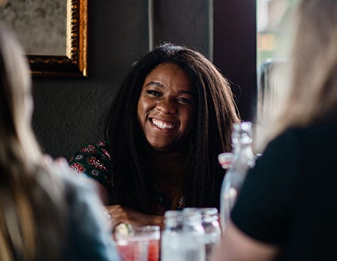 A woman smiles, enjoying the company at the restaurant.