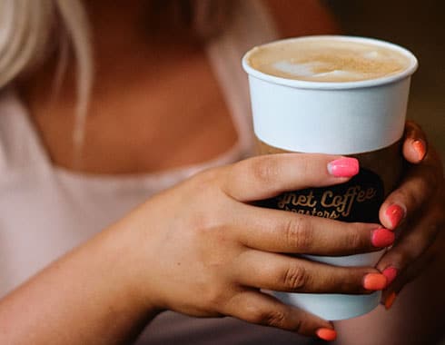An artfully crafted latte is held in a woman's hands.