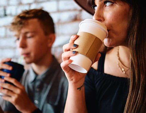 Mother and son enjoy coffee together in front of an aged brick wall.