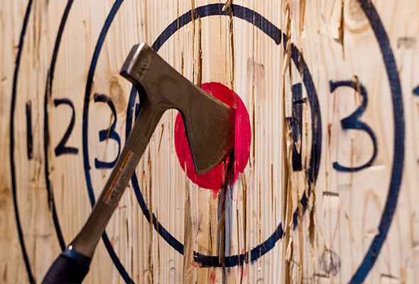 A thrown axe is firmly planted in the middle of a bullseye.