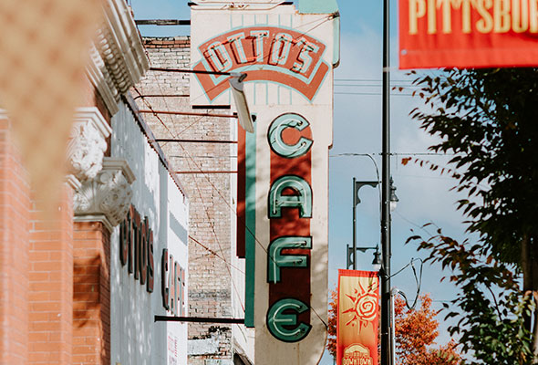 An old sign is attached to Otto's Cafe, hanging high above Broadway Street in Pittsburg, Kansas.