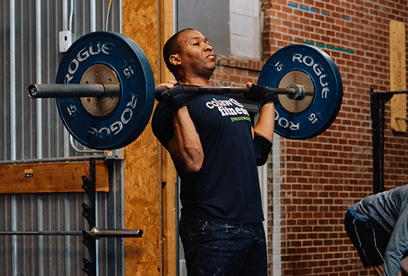 A man dead lifts up to his shoulders as he prepares to go higher at Crossfit 620.